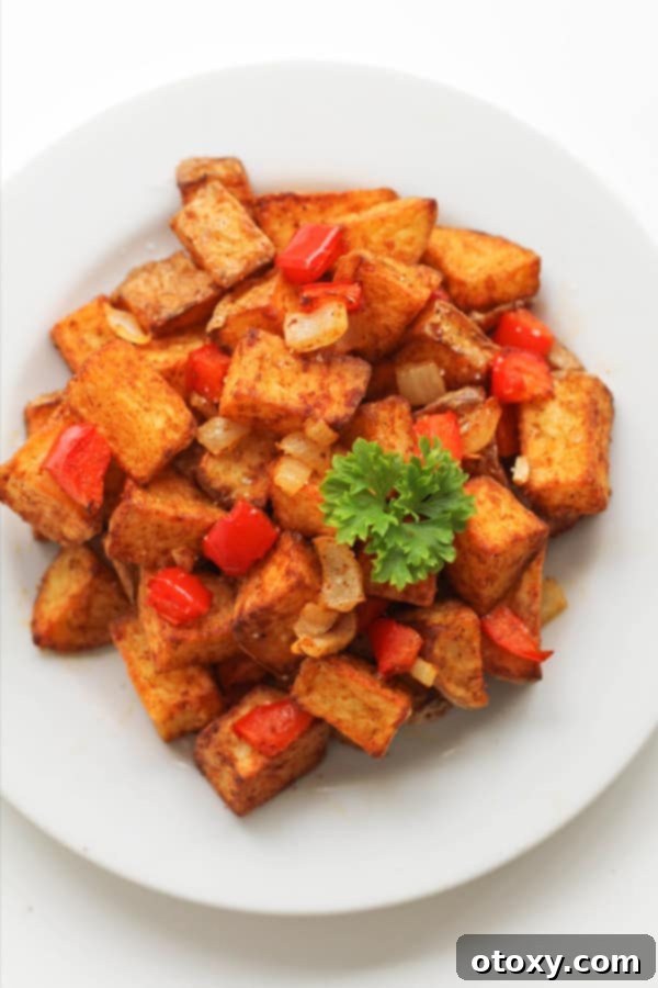 Crispy air fryer breakfast potatoes on a white plate, garnished with fresh parsley.