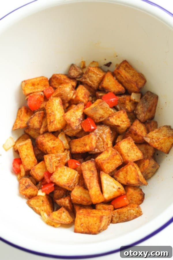 A white bowl filled with perfectly golden and crispy air fryer breakfast potatoes.