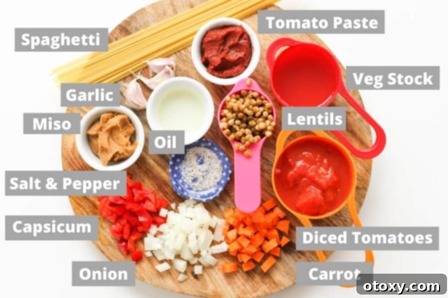 A collection of fresh ingredients for lentil bolognese arranged neatly on a rustic wooden board.