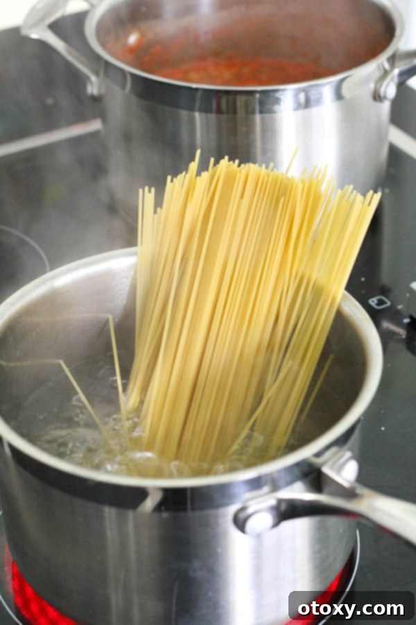 Long strands of spaghetti boiling in a large pot of salted water.