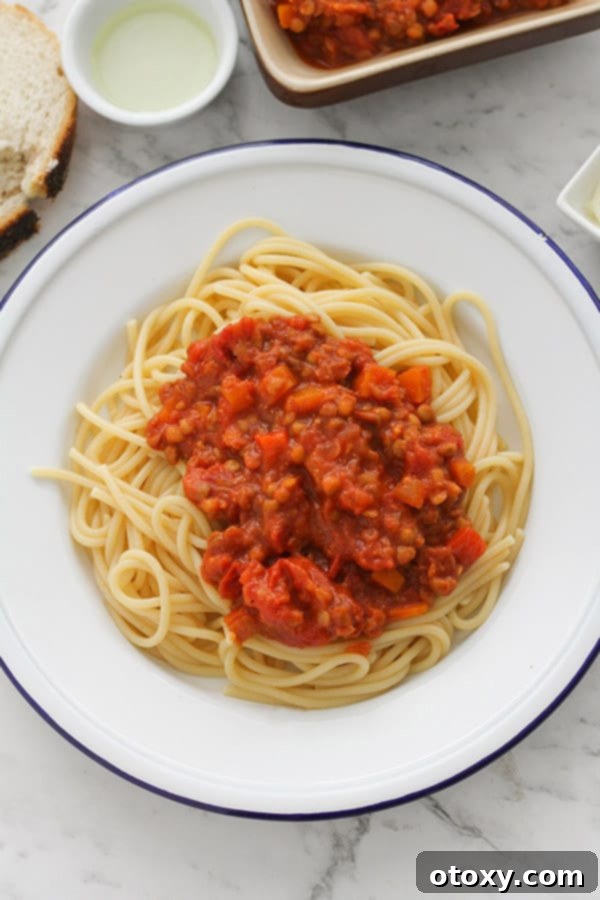 A final shot of delicious lentil bolognese with spaghetti on a white plate, ready to be enjoyed.
