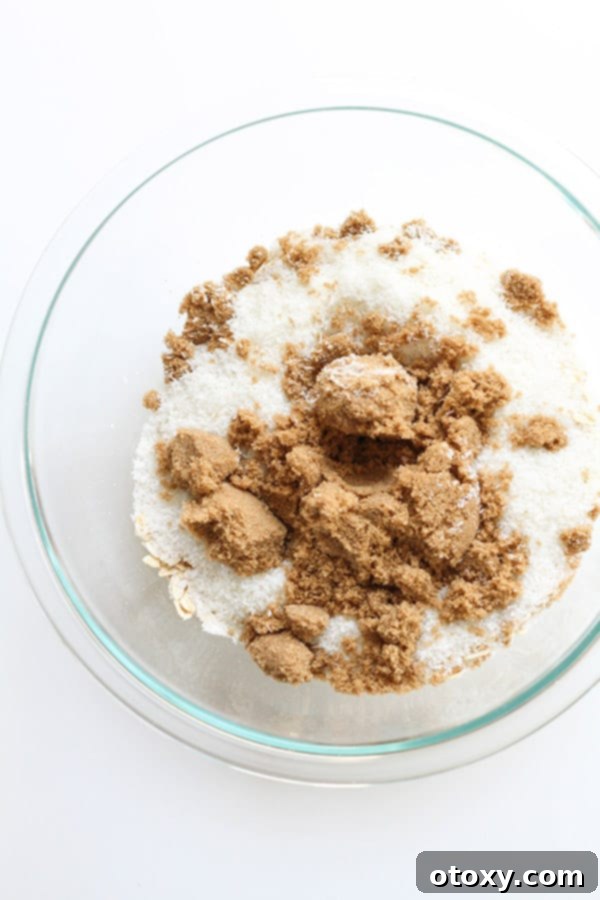 Anzac Golden Oat Bar 5 A glass mixing bowl filled with dry ingredients for Anzac slice: oats, flour, brown sugar, and desiccated coconut, ready for the next step.