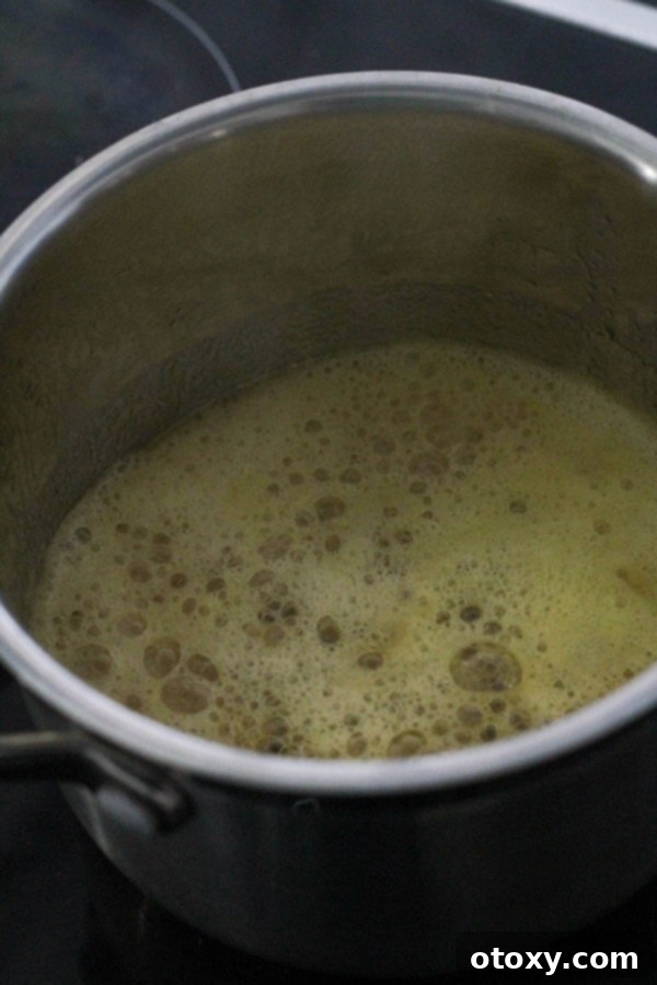 Anzac Golden Oat Bar 6 A saucepan on a stovetop, showing melted butter and golden syrup bubbling gently, preparing for the wet ingredients of the Anzac slice.
