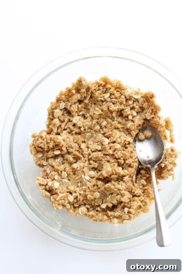 Anzac Golden Oat Bar 7 The combined Anzac slice mixture in a large glass bowl, showing the wet ingredients fully incorporated into the dry, creating a sticky, golden dough.