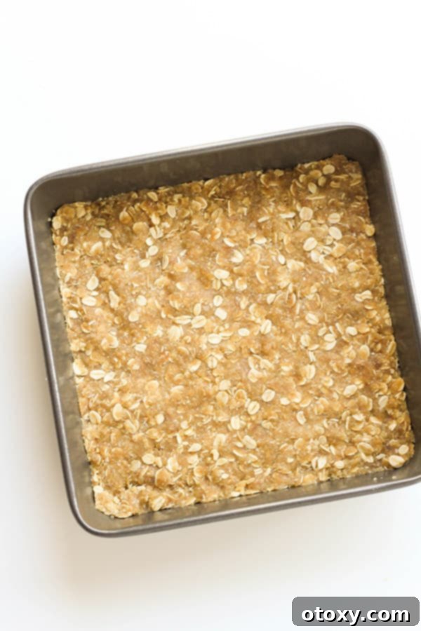 Anzac Golden Oat Bar 8 Unbaked Anzac slice mixture pressed evenly into a slice pan, with a golden surface ready to be baked to perfection.