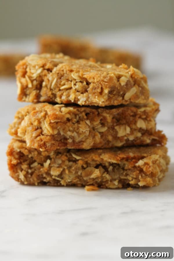 Anzac Golden Oat Bar 10 Multiple pieces of Anzac slice layered on top of each other, displaying their rich golden color and appealing chewy texture.