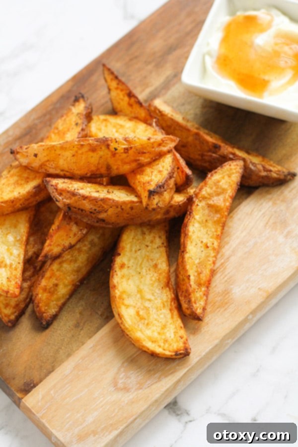 potato wedges and dipping sauce on a wooden cutting board.