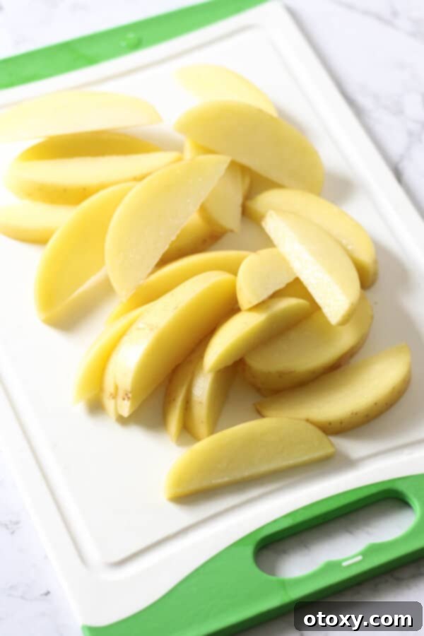 potatoes cut into thin wedges on a cutting board.