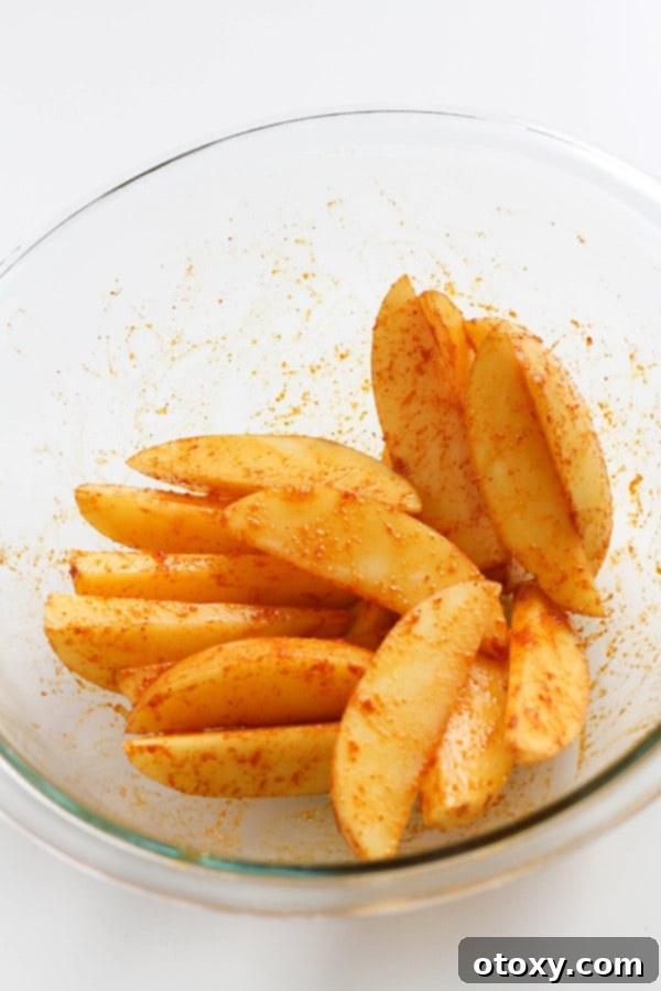 potatoes covered in seasoning in a glass bowl.