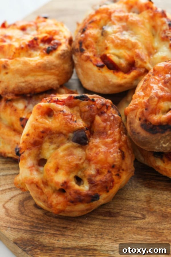 A close-up of vegetarian pizza scrolls on a wooden cutting board, showcasing their golden crust and cheesy filling.