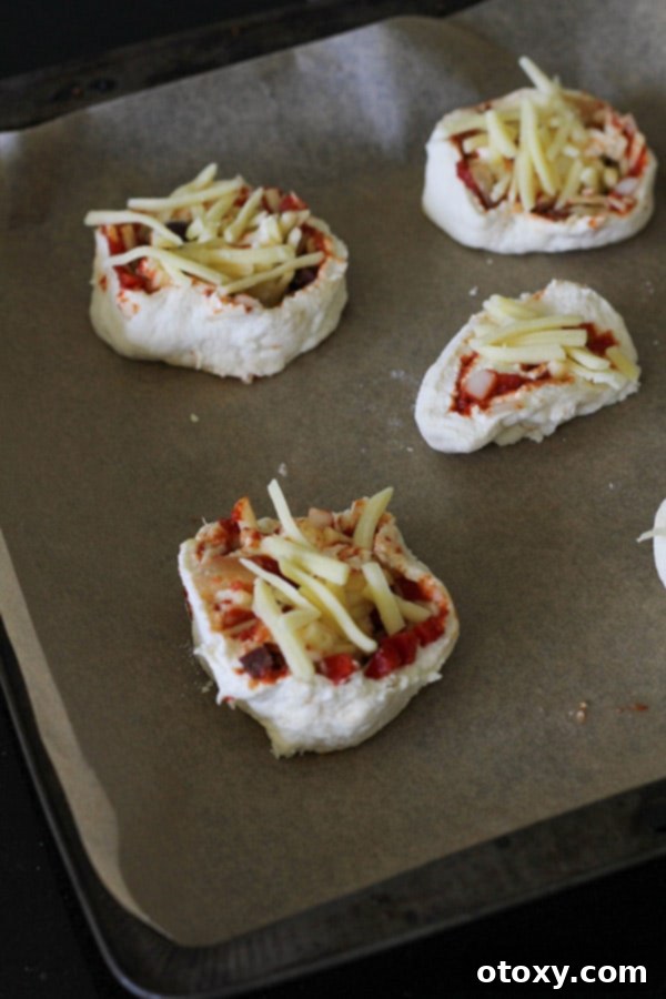 Uncooked vegetarian pizza rolls neatly arranged on a baking tray, ready for the oven.