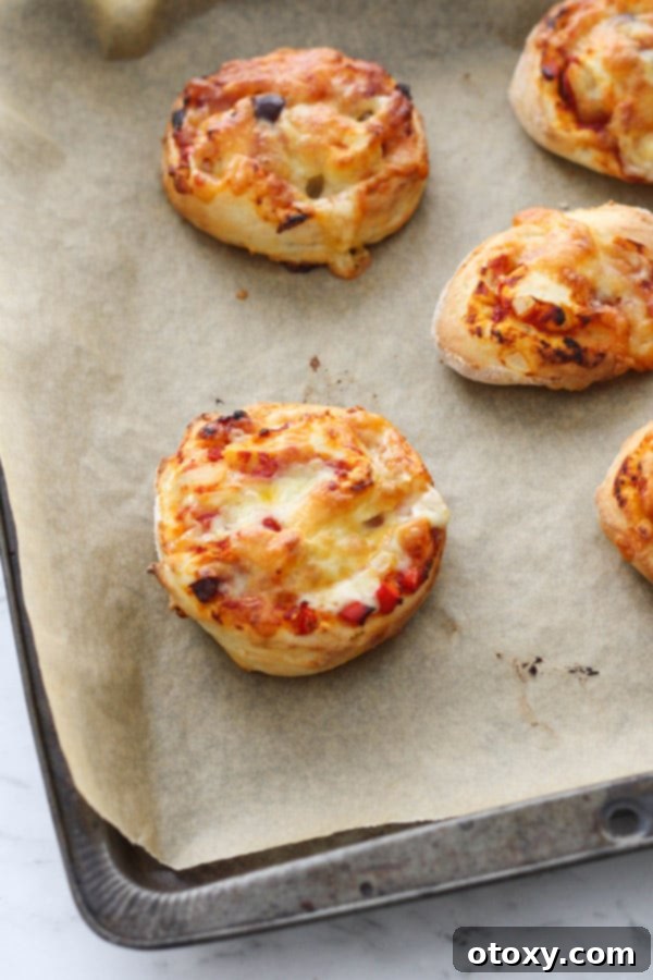 Freshly baked vegetarian pizza rolls on a baking tray, hot out of the oven.