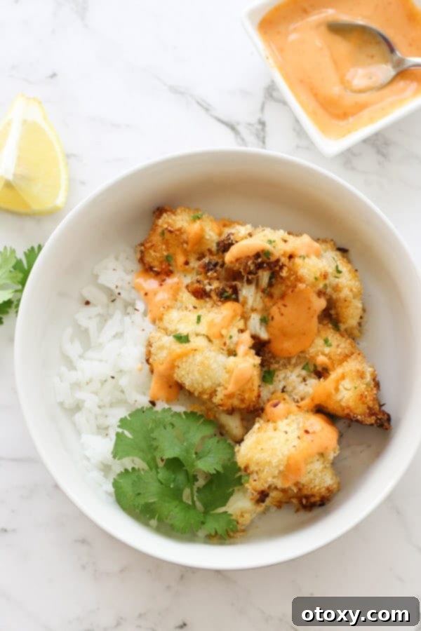 Crispy Bang Bang Cauliflower Oven and Air Fryer 2 Crispy Bang Bang Cauliflower served over a bed of fluffy white rice, garnished with fresh herbs.