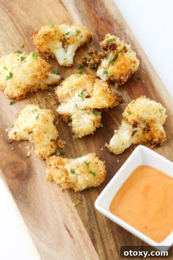 Crispy Bang Bang Cauliflower Oven and Air Fryer 11 A rustic wooden serving board laden with freshly cooked, golden-brown Bang Bang Cauliflower pieces, ready to be enjoyed.