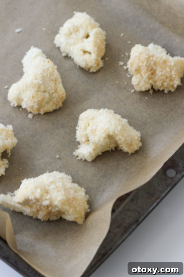 Crispy Bang Bang Cauliflower Oven and Air Fryer 6 Cauliflower pieces, perfectly coated in breadcrumbs, neatly arranged on a baking tray before entering the oven.