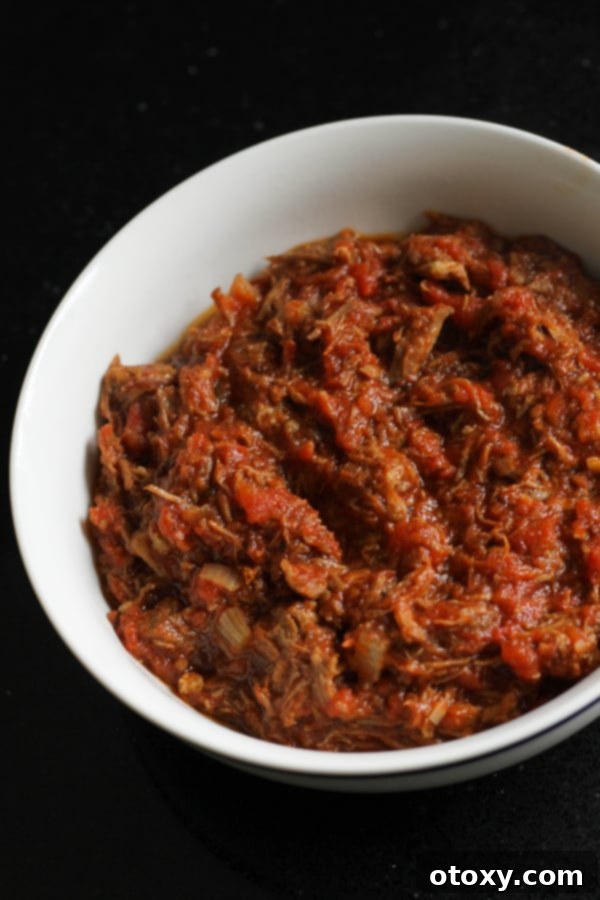 braised beef in a white bowl, garnished with fresh parsley.