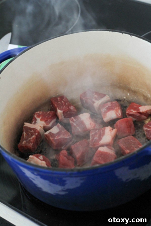 cubes of beef browning in a dutch oven on the stovetop.