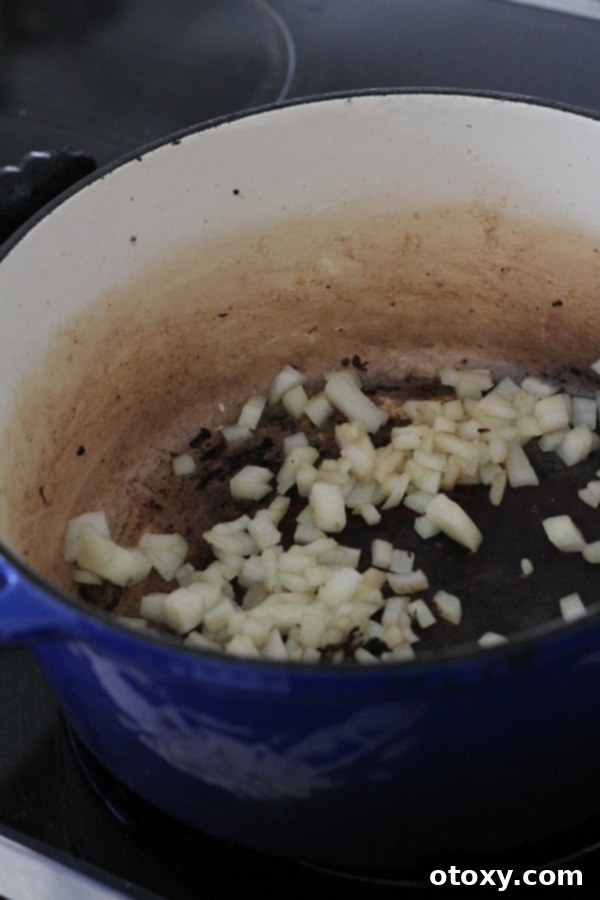 diced onion cooking in a dutch oven, becoming softened and golden.