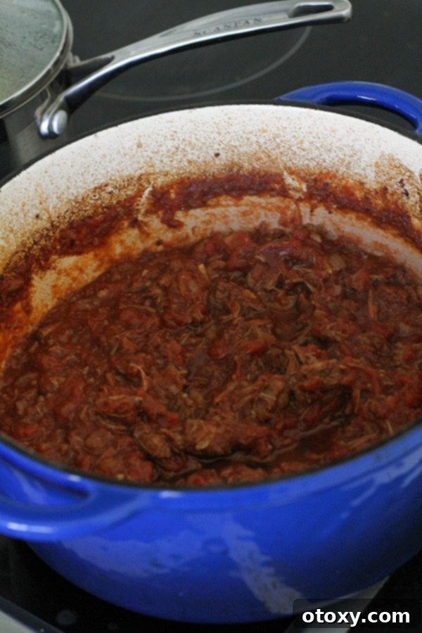 shredded braised beef in a dutch oven, mixed with the rich sauce.