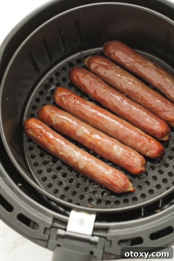 Perfectly cooked sausages resting in an air fryer basket, ready to be served.
