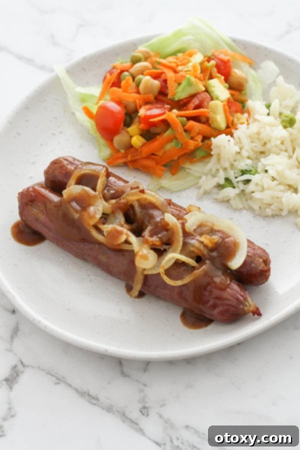 Flavorful sausages on a plate, generously covered with caramelized onions and rich gravy.
