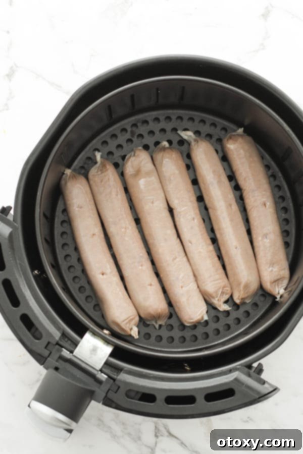 Uncooked sausages arranged neatly in an air fryer basket, ready for cooking.