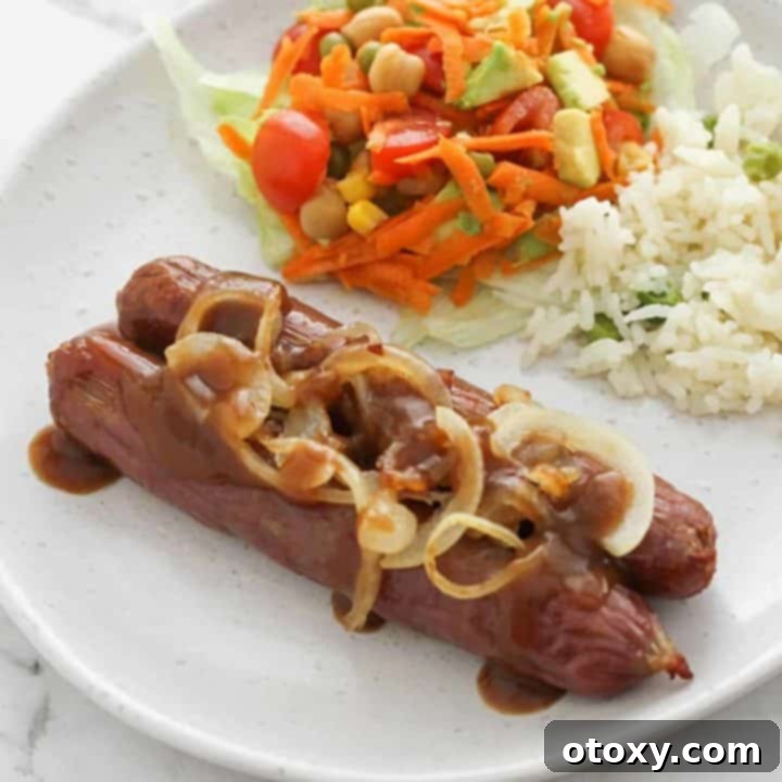 Sausages on a white plate topped with onions and gravy, a delightful air fryer meal.