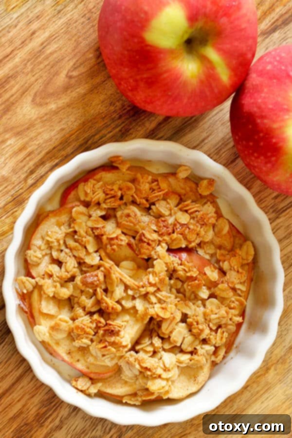 Close-up of a single serving healthy apple crisp with oat topping in a ramekin, ready to eat.