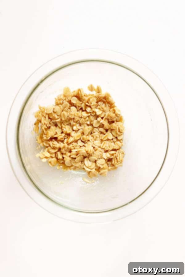 Bowl of healthy apple crisp topping ingredients, including oats, flour, and cinnamon, ready to be mixed.