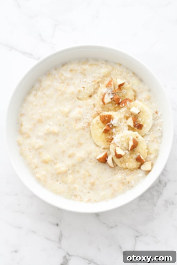 Golden Banana Breakfast Bowl 8 A close-up of a delectable bowl of banana porridge, artfully garnished with vibrant banana slices, a dusting of cinnamon, crunchy almonds, and delicate shredded coconut, inviting you to indulge.