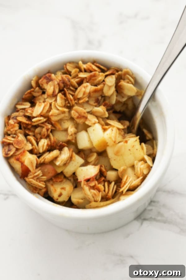 Delicious Air Fryer Apple Crisp in a white ramekin with a spoon, ready to be enjoyed.