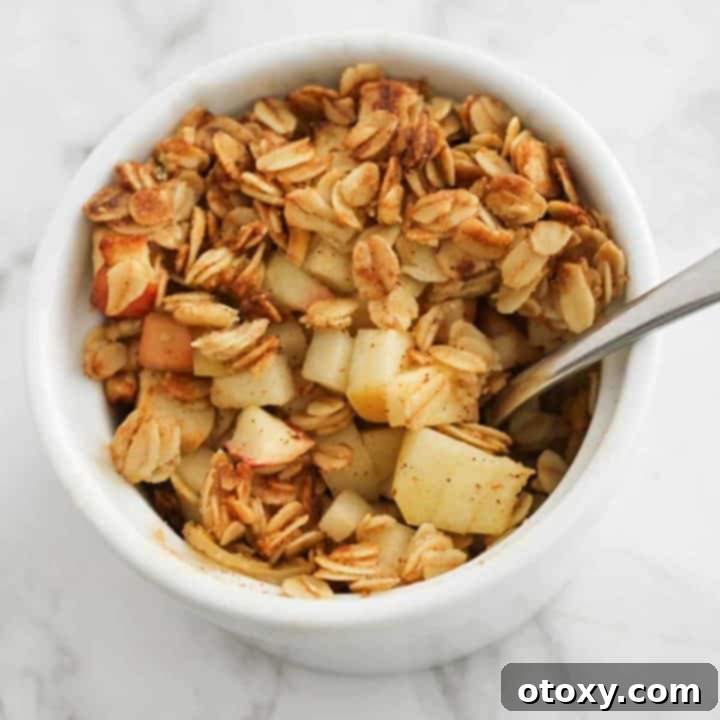 Air Fryer Apple Crisp in a white ramekin with a spoon, highlighting its warm, inviting appearance.