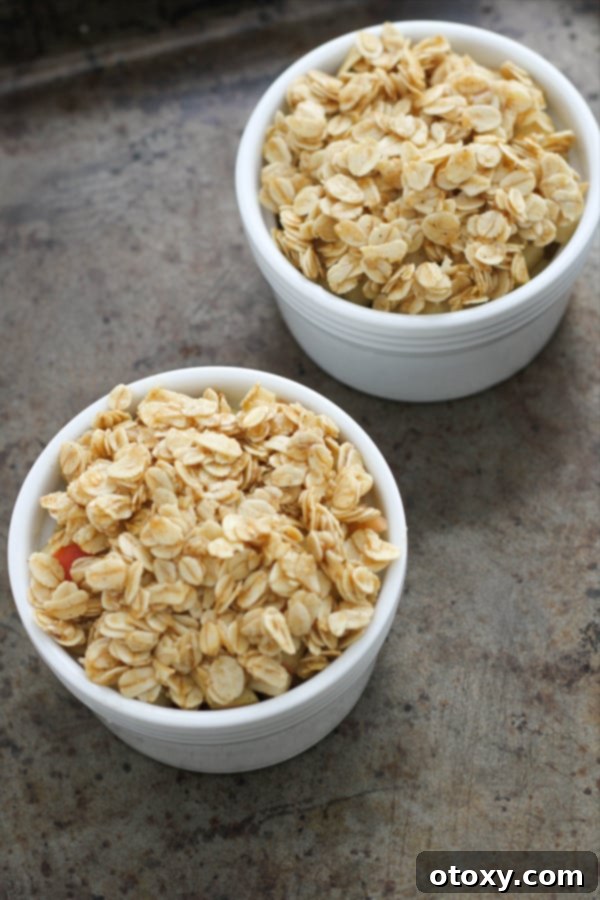 Two individual apple crisps in white ramekins, topped with crumb mixture, ready for the air fryer.