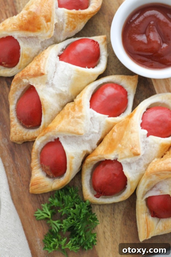 Crispy Air Fryer Sausage Bites 2 Crispy Air Fryer Pigs in a Blanket served on a rustic wooden board, ready for snacking.