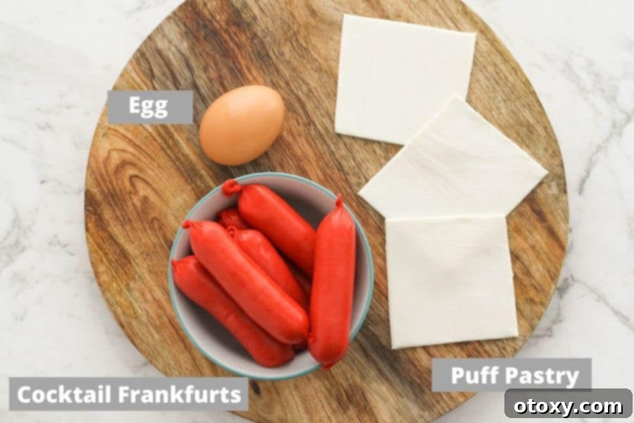 Crispy Air Fryer Sausage Bites 4 Ingredients for pigs in a blanket: mini hotdogs, puff pastry, and an egg, displayed on a wooden board.