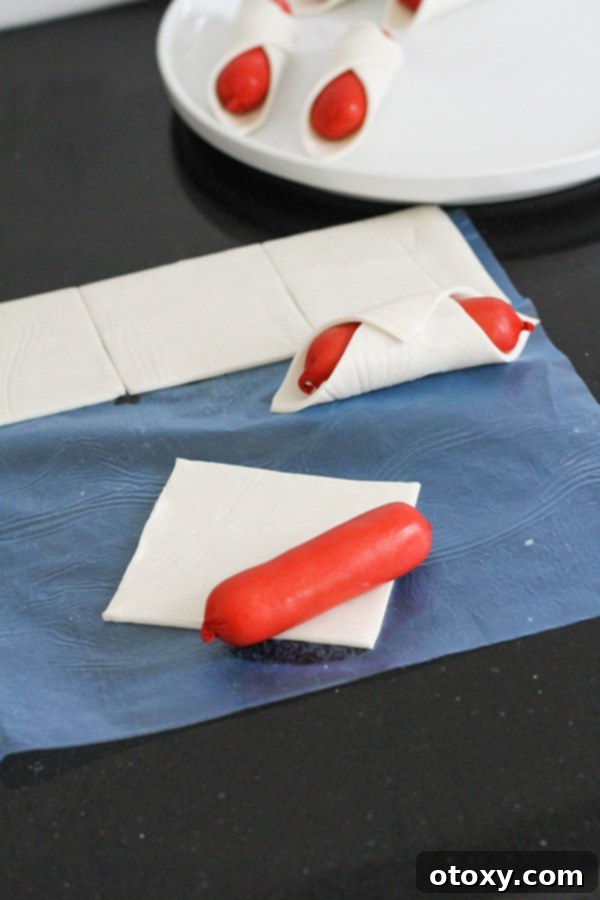 Crispy Air Fryer Sausage Bites 5 A mini hotdog placed diagonally on a square of puff pastry, ready to be wrapped.