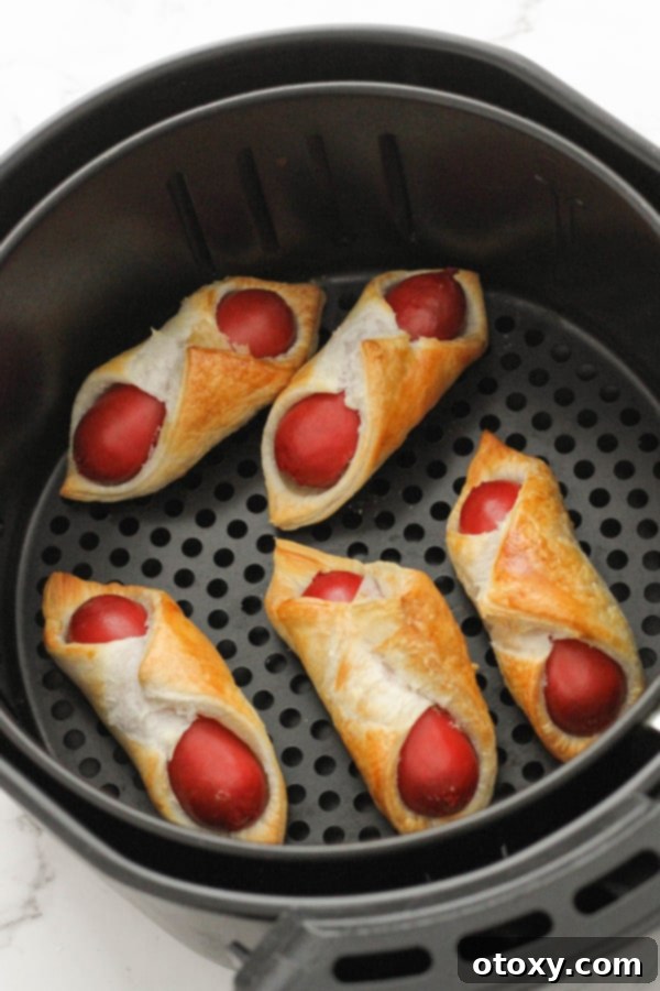 Crispy Air Fryer Sausage Bites 8 Freshly cooked pigs in a blanket, golden brown and crispy, inside an air fryer basket.