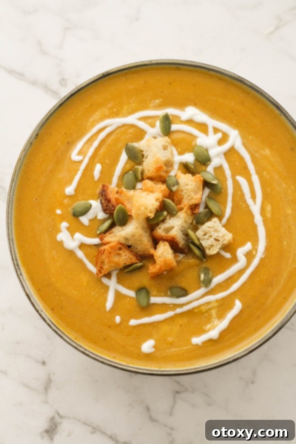 Rich, creamy pumpkin and cauliflower soup, topped with crispy croutons and vibrant pumpkin seeds, served in an elegant bowl.