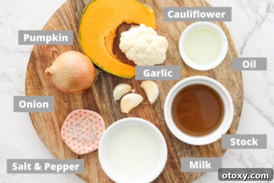 A rustic wooden board showcasing the fresh ingredients required for pumpkin and cauliflower soup: pumpkin chunks, cauliflower florets, whole garlic cloves, and an onion.