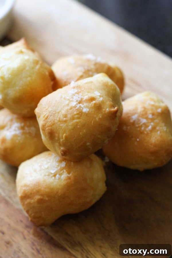 Stacked two-ingredient dough pretzel bites on a rustic wooden serving board, sprinkled with coarse salt, ready to be enjoyed.