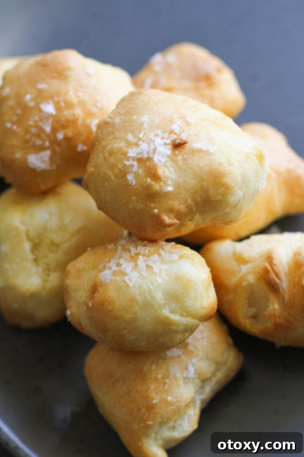 A close-up of a generous serving of freshly baked, soft pretzel bites, piled high on a white plate.