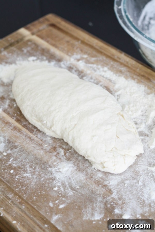 Freshly kneaded two-ingredient dough, smooth and ready for shaping, resting on a wooden cutting board dusted with flour.