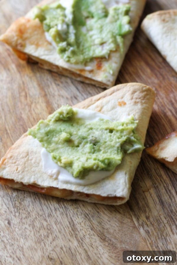 quesadilla quarters on a wooden board topped with guacamole and greek yoghurt.