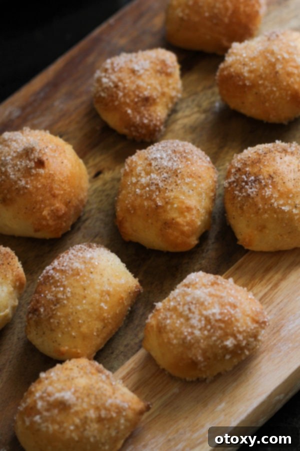 Freshly baked cinnamon sugar pretzel bites generously coated and piled on a rustic wooden board.