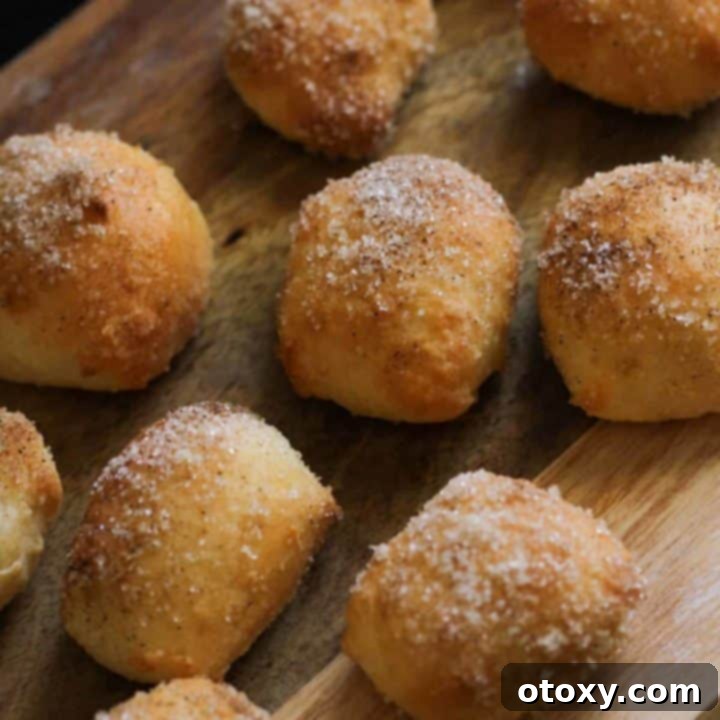 Freshly baked cinnamon sugar pretzel bites generously coated and piled on a rustic wooden board.