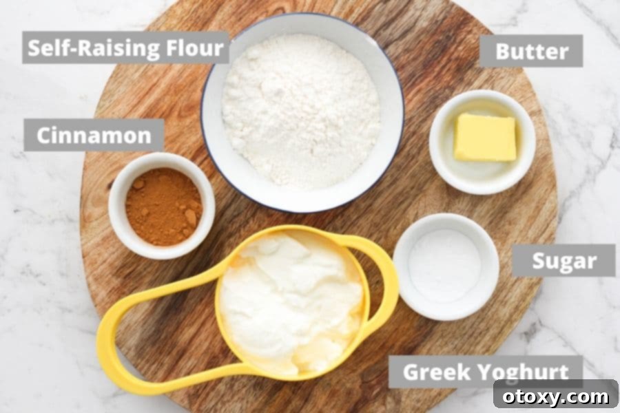 A collection of essential ingredients including Greek yogurt, flour, butter, cinnamon, and sugar laid out on a wooden serving board.