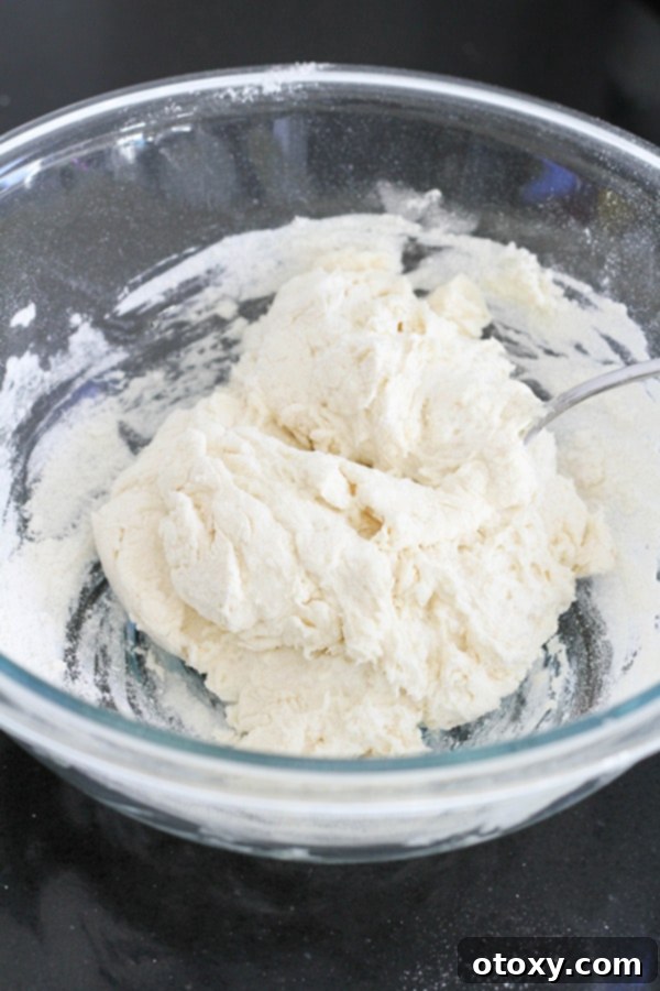 Two-ingredient dough in a clear glass mixing bowl, showing a slightly shaggy consistency.