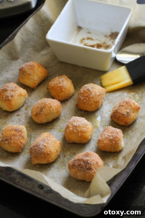 Baked cinnamon sugar pretzel bites, glistening with butter and sugar, still on the baking tray.