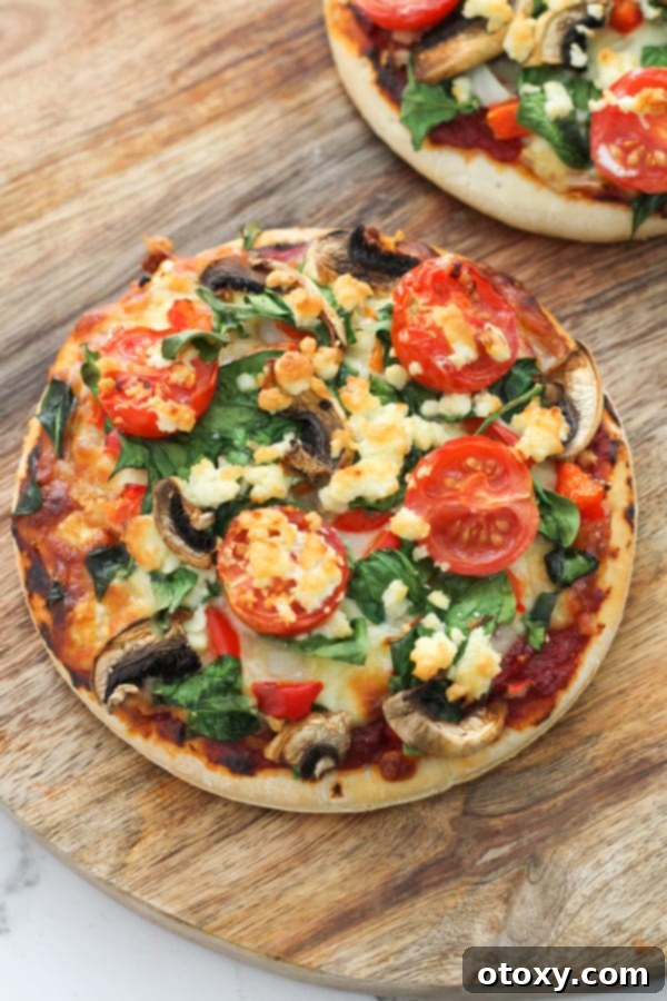 Mediterranean Greens and Feta Pizza 2 Two spinach and feta pizzas on a rustic wooden serving board, garnished with fresh basil.
