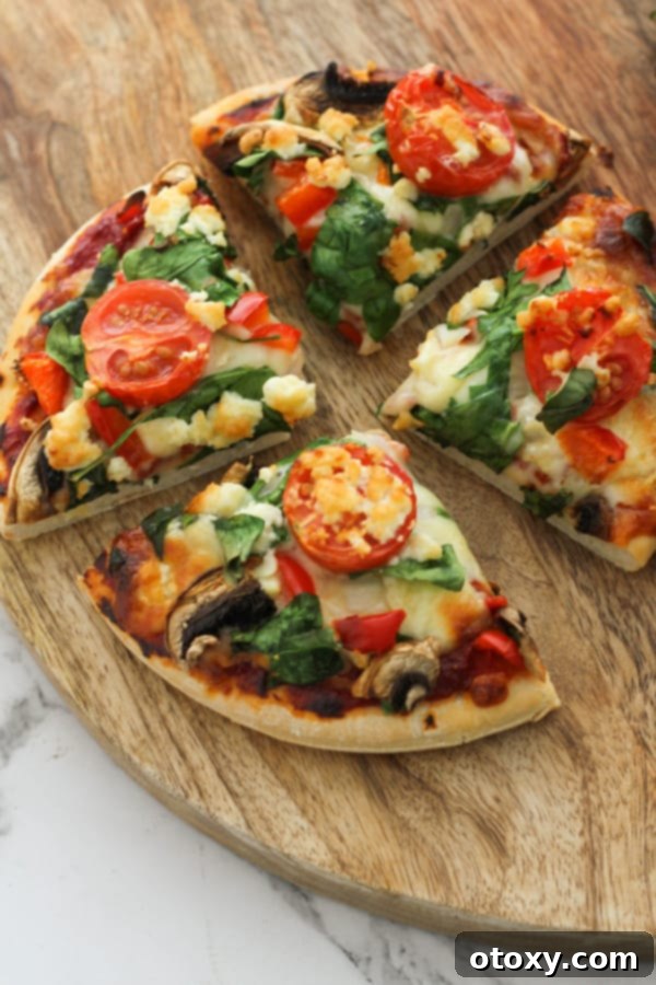 Mediterranean Greens and Feta Pizza 7 Spinach and feta pizza cut into quarters on a wooden serving board.